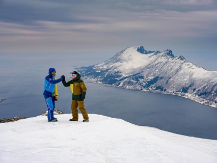 Two ski mountaineers congratulate each other at the summit of Flobjoern overlooking the Bergsfjord