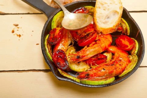 Roasted shrimps on cast iron skillet with zucchini and tomatoes