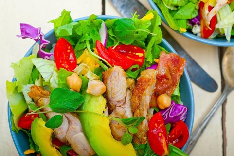 Fresh and healthy Chicken Avocado salad over rustic wood table