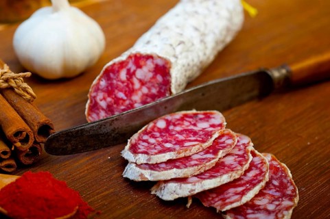 Traditional Italian salame cured sausage sliced on a wood board