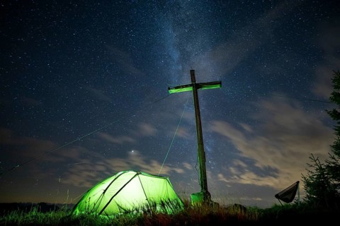 Green tent with summit cross under a starry sky on Portlakopf