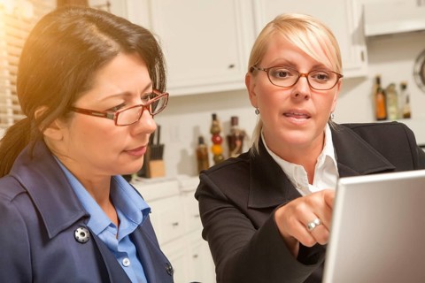 Businesswomen working on the laptop together in the kitchen