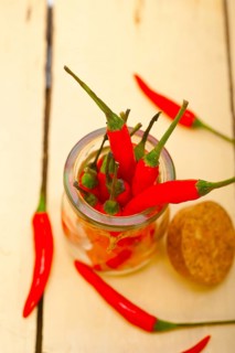 Red chili peppers on a glass jar over white wood rustic table