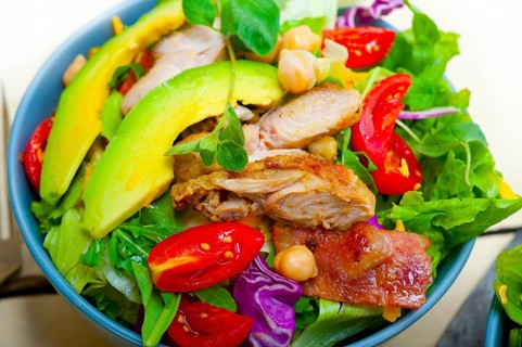 Fresh and healthy Chicken Avocado salad over rustic wood table