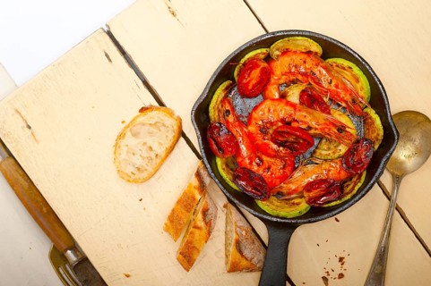Roasted shrimps on cast iron skillet with zucchini and tomatoes