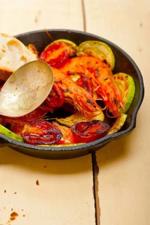 Roasted shrimps on cast iron skillet with zucchini and tomatoes