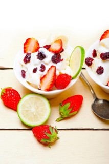 Fruit and yogurt salad healthy breakfast over white wood table