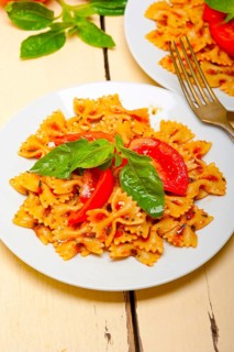 Italian pasta farfalle butterfly bow-tie with tomato basil sauce over white rustic wood table
