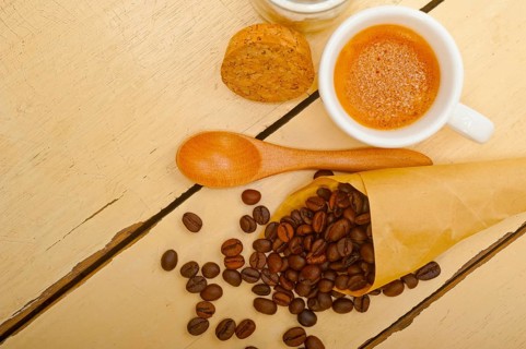 Espresso coffee and beans on a paper cone cornucopia over white background