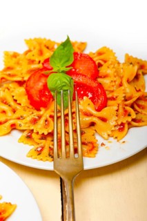 Italian pasta farfalle butterfly bow-tie with tomato basil sauce over white rustic wood table