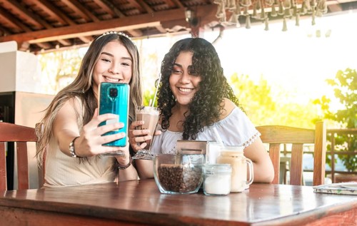 Two girls taking a selfie and drinking coffee