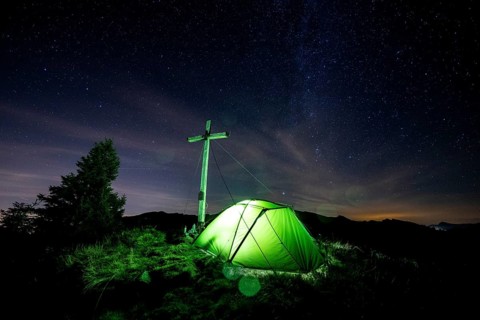 Green tent with summit cross under a starry sky on Portlakopf