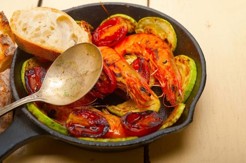 Roasted shrimps on cast iron skillet with zucchini and tomatoes