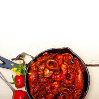 Fresh seafood stew prepared on an iron skillet ove white rustic wood table