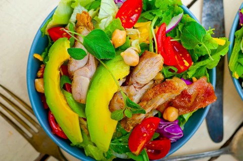 Fresh and healthy Chicken Avocado salad over rustic wood table