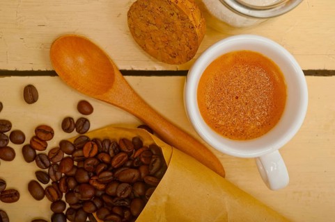 Espresso coffee and beans on a paper cone cornucopia over white background
