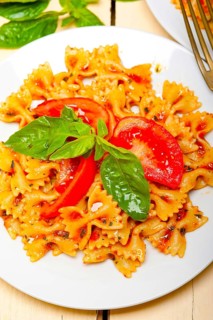 Italian pasta farfalle butterfly bow-tie with tomato basil sauce over white rustic wood table