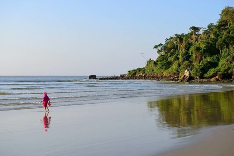 Little girl with sand bucket on lonely beach