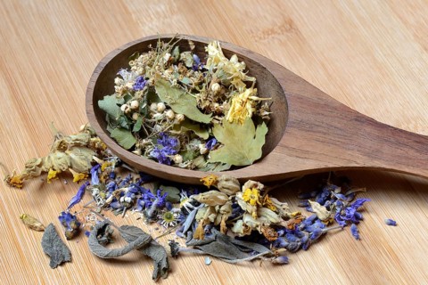 Tea mixture in wooden ladle and medicinal plants