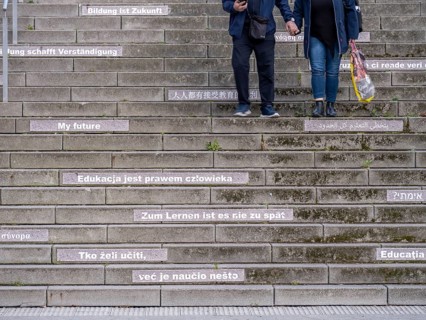A couple walking down stairs with slogans about education and learning in several languages
