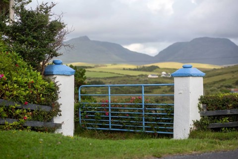 Entrance gate with white and blur piers against a mountain background in Sligo