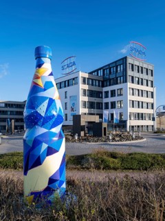 Building of the pharmaceutical company Stada Arzneimittel AG behind an oversized mineral water bottle