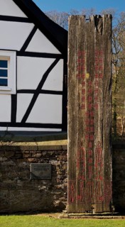 Wooden stele made of ship planks in front of half-timbered house at St. Pancratius Church on the occasion of the 1000th anniversary of the parish