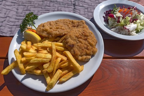 Wiener Schnitzel with french fries and salad served in a garden restaurant