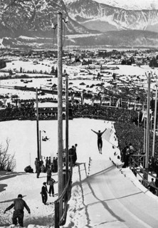 View of snow-covered Garmisch-Partenkirchen and the sixty thousand spectators in the ski stadium during the jumping from the small hill in the combination cross-country skiing