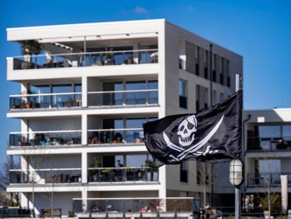 Pirate flag in front of condominiums in the new development Hafeninsel Mitte am Alten Hafen