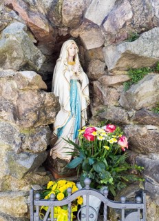 Virgin Mary figure with rosary and flowers