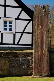Wooden stele made of ship planks in front of half-timbered house at St. Pancratius Church on the occasion of the 1000th anniversary of the parish