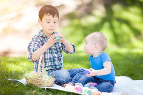 mixed-race chinese and caucasian boys outside in park playing with easter eggs
