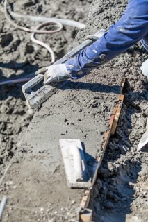 Pool construction worker working with A smoother rod on wet concrete