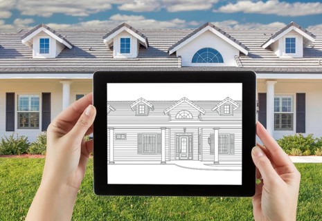 Female hands holding computer tablet with house drawing on screen
