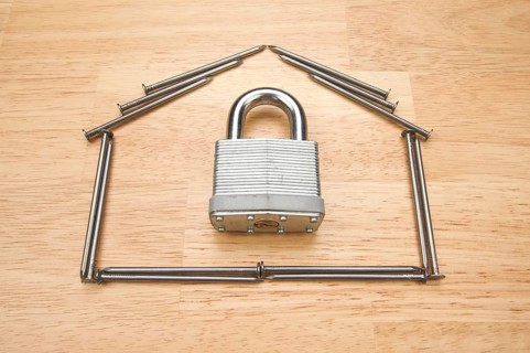 House of nails with lock on a wood background