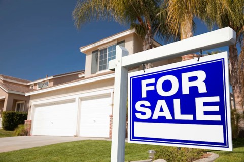 For sale real estate sign in front of house