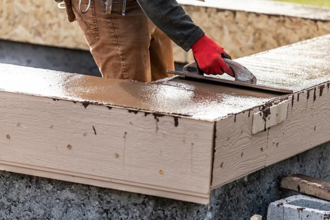 Construction worker using wood trowel on wet cement forming coping around new pool