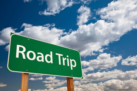 Road trip green road sign with dramatic sky and clouds