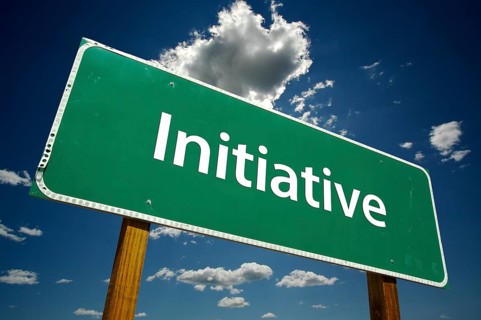 Initiative green road sign over dramatic blue sky and clouds with clipping path