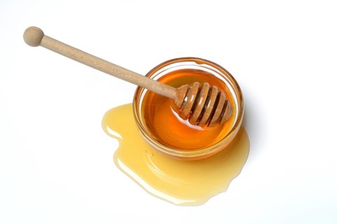 Bienenhonig mit Honigloeffel in Schale