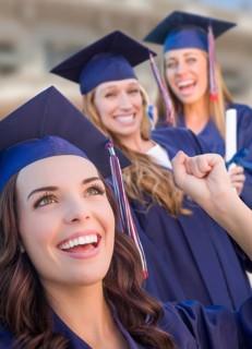 Happy graduating group of girls in cap and gown celebrating on campus