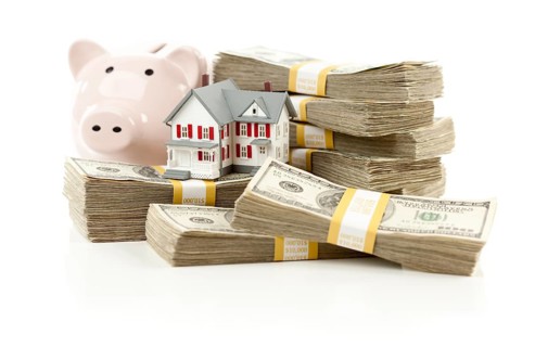 Small house and piggy bank with stacks of hundred dollar bills isolated on a white background