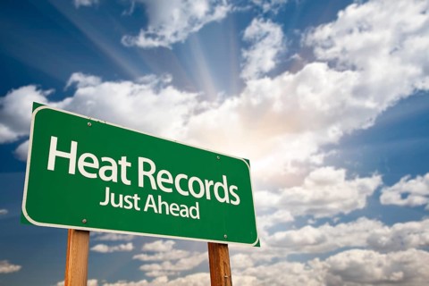 Heat records green road sign against dramatic sky