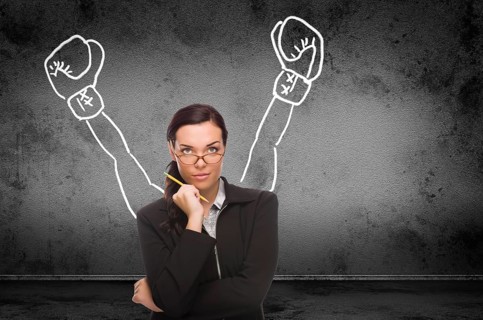 Young adult woman with pencil in front of boxing gloves on hands drawing on wall with copy sapce