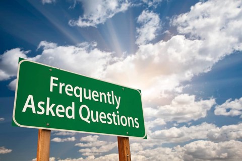 Frequently asked questions green road sign with dramatic clouds and sky
