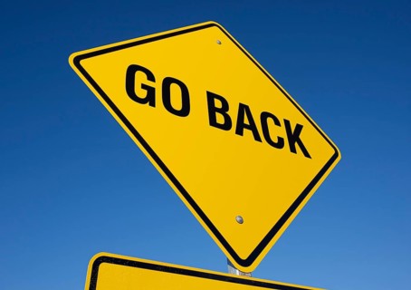 Go back yellow road sign against a deep blue sky with clipping path