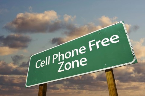 Cell phone free zone green road sign in front of dramatic clouds and sky