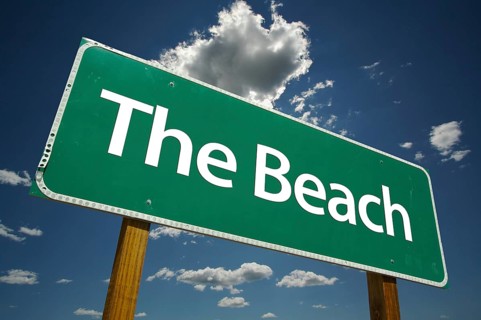 The beach green road sign with dramatic clouds and sky