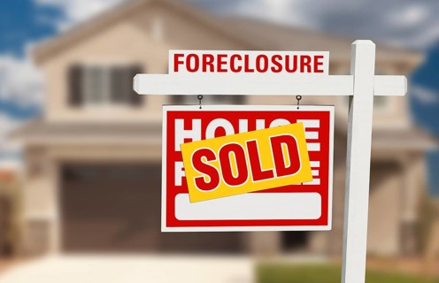Sold foreclosure home for sale sign and house with dramatic sky background